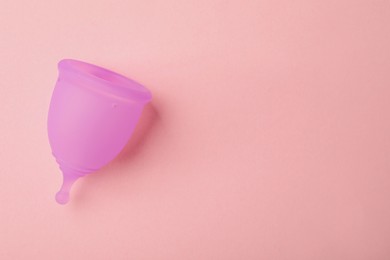 Photo of Menstrual cup on pink background, top view. Space for text