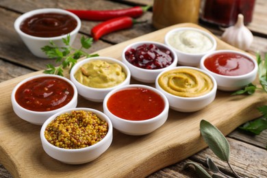 Different tasty sauces in bowls and ingredients on wooden table, closeup