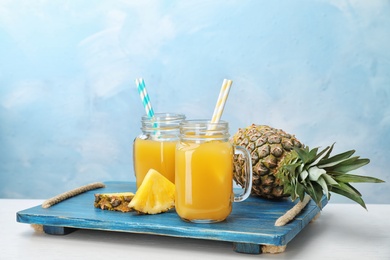 Photo of Mason jars with delicious pineapple juice on table