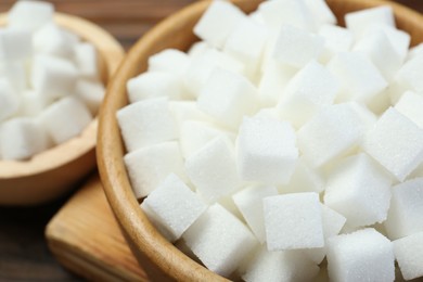 Photo of White sugar cubes on wooden table, closeup