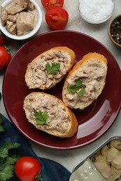 Photo of Tasty sandwiches with cod liver and different products on light grey table, flat lay