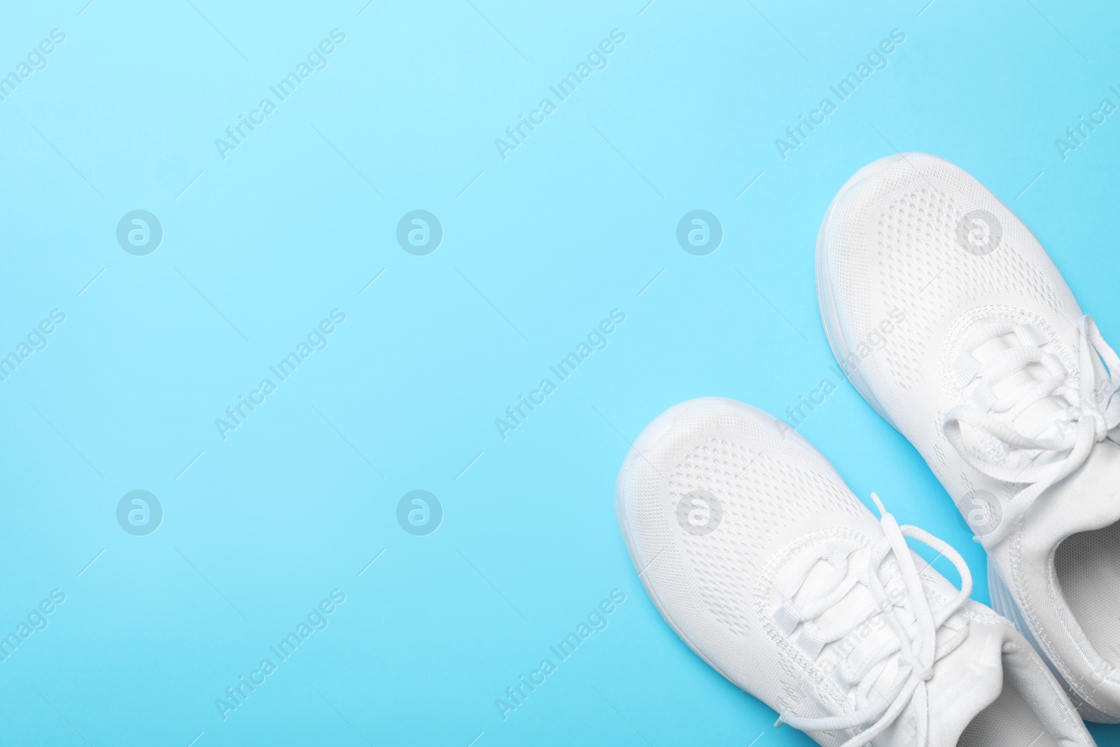 Photo of Stylish sport shoes on light blue background, flat lay. Space for text
