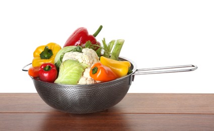 Photo of Metal colander with different vegetables on wooden table against white background