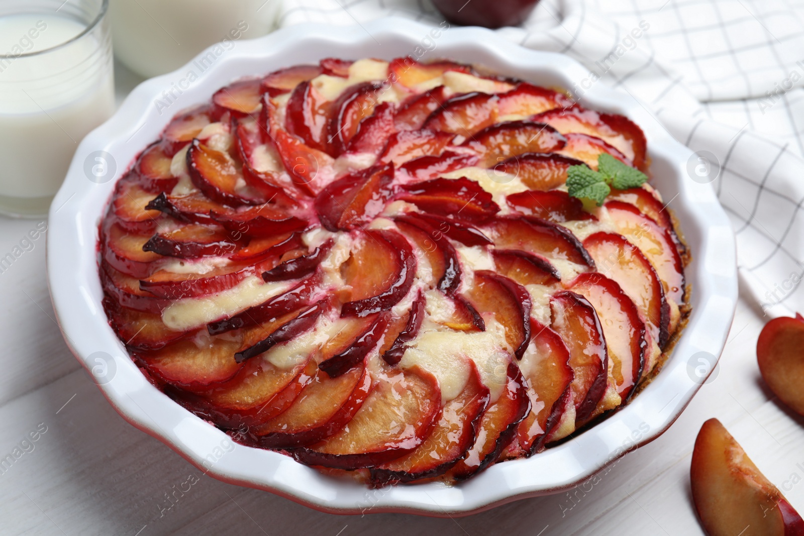 Photo of Delicious cake with plums on white wooden table, closeup