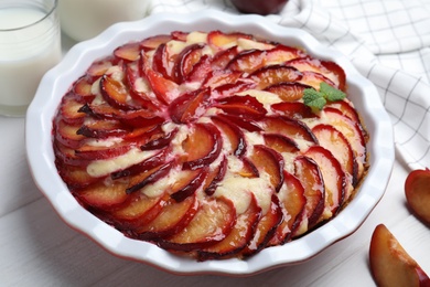 Delicious cake with plums on white wooden table, closeup