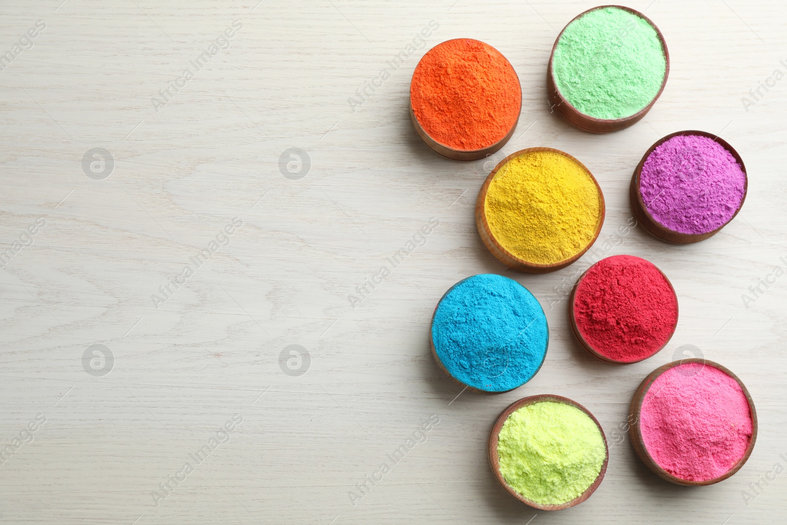 Photo of Colorful powder dyes on white wooden background, flat lay with space for text. Holi festival