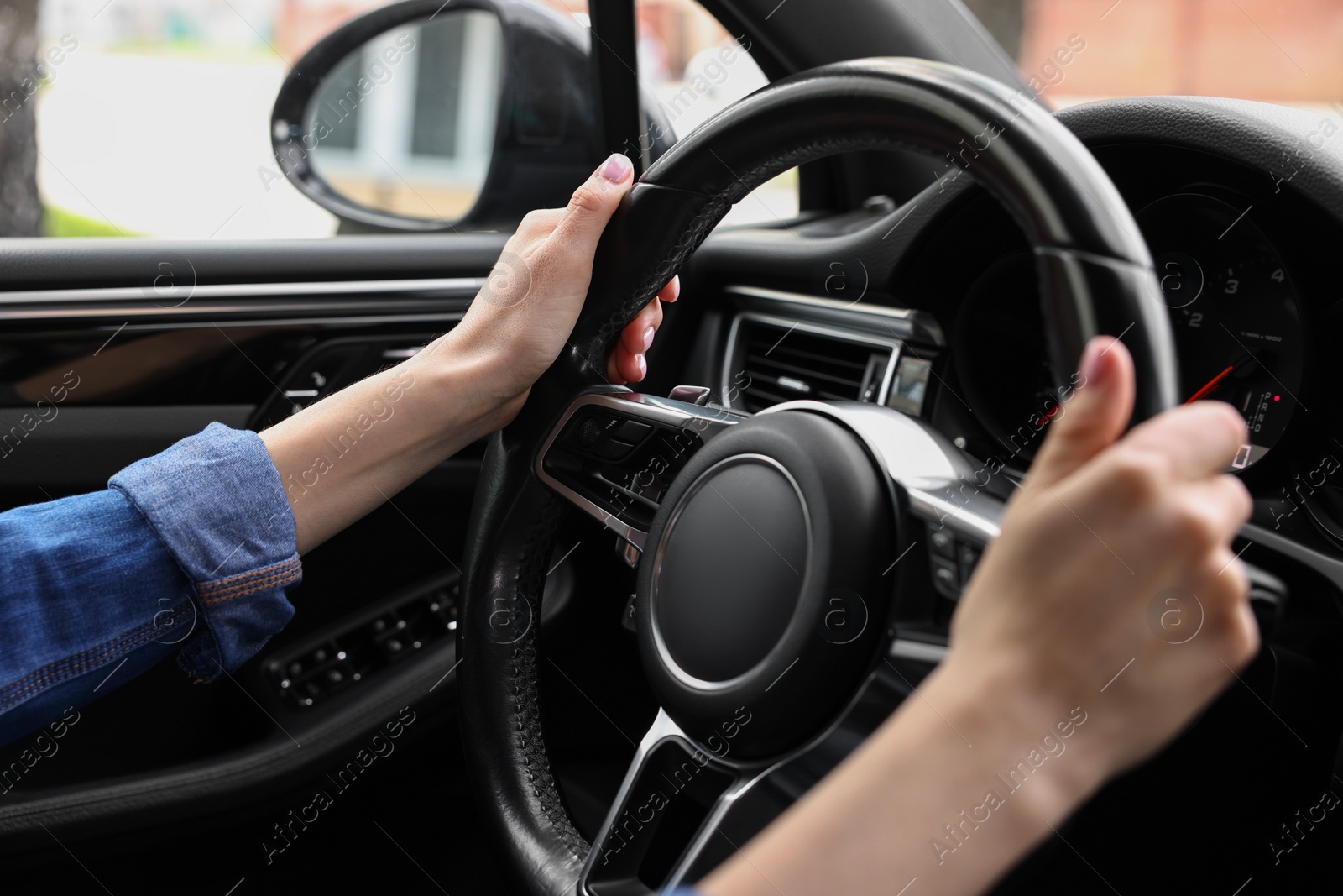 Photo of Woman holding steering wheel while driving her car, closeup