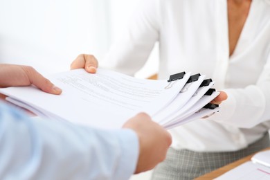 Man giving documents to colleague in office, closeup