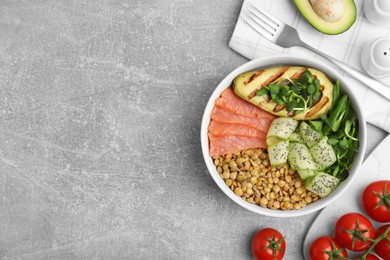 Delicious lentil bowl with salmon, avocado and cucumber on grey table, flat lay. Space for text