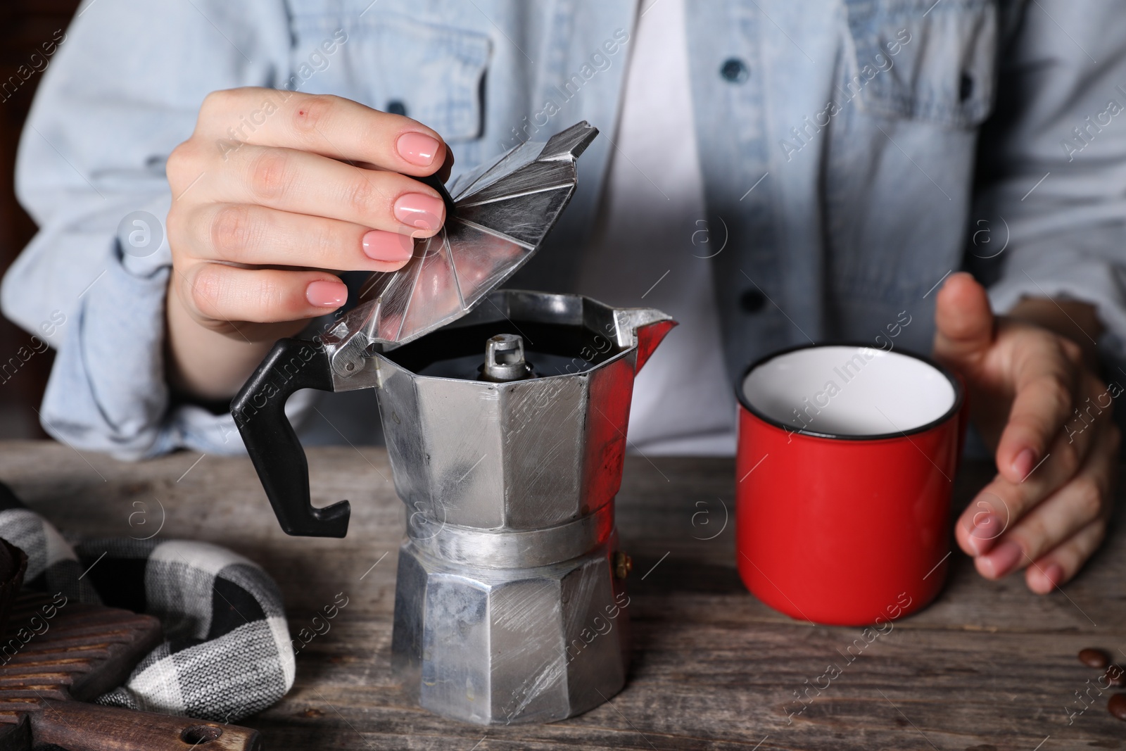 Photo of Brewing coffee. Woman with moka pot and cup at wooden table, closeup