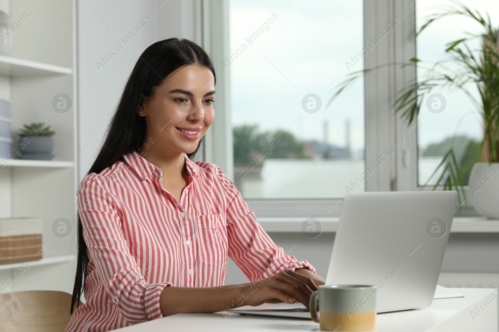 Photo of Young woman working with laptop at workplace in office