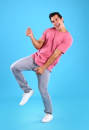 Photo of Handsome young man dancing on blue background