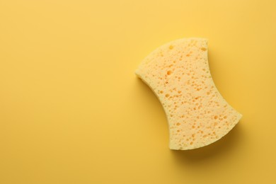 Sponge on yellow background, top view. Space for text