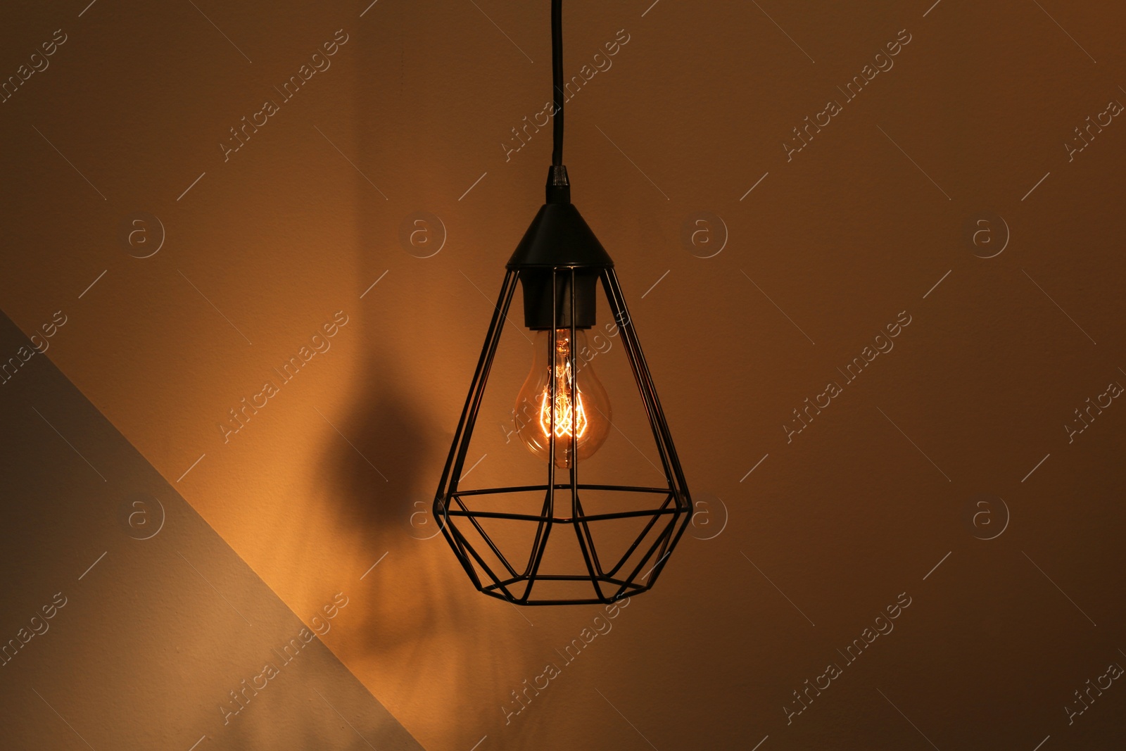 Photo of Hanging lamp bulb in chandelier against color background