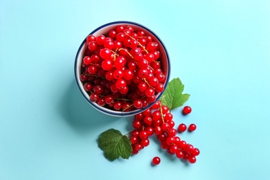 Delicious red currants and leaves on light blue background, flat lay