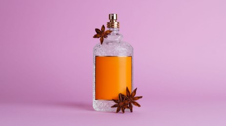Photo of Bottle of luxurious perfume and anise on light purple background
