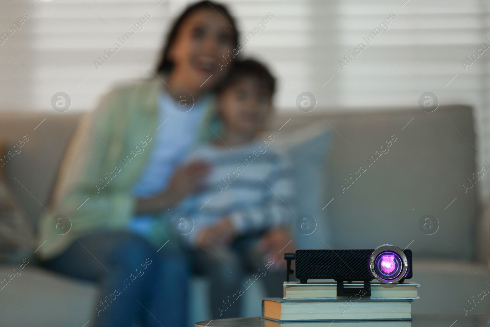 Photo of Young woman and her son watching movie at home, focus on video projector