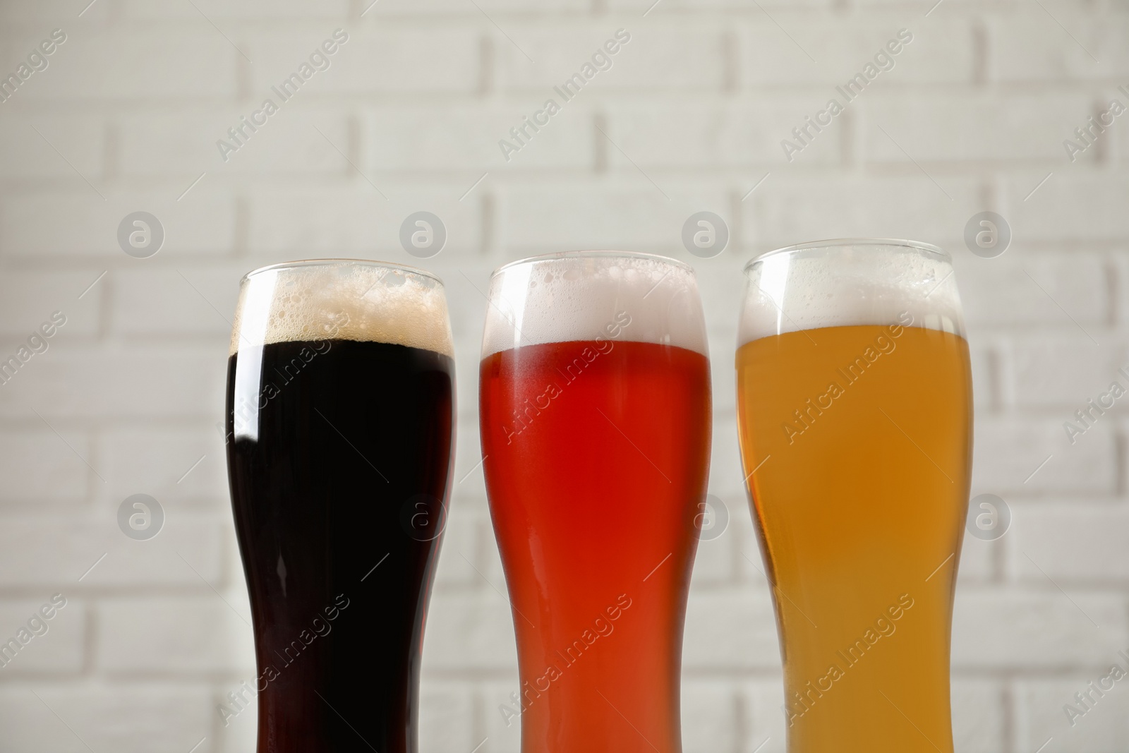 Photo of Glasses with different types of cold tasty beer on blurred background