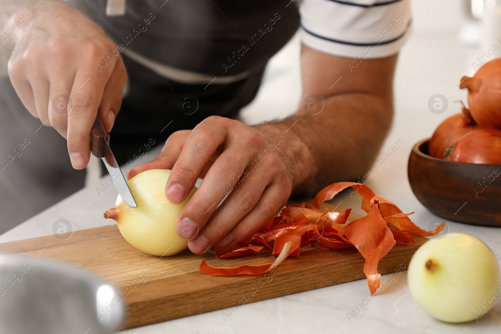 Photo of Man peeling onion at kitchen counter, closeup. Preparing vegetable