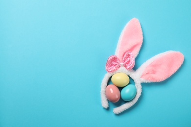 Photo of Funny headband with Easter bunny ears and dyed eggs on color background, flat lay. Space for text