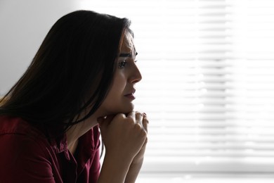 Abused young woman crying indoors, space for text. Domestic violence concept