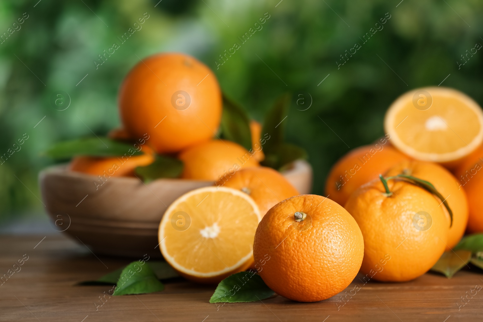 Photo of Fresh ripe oranges on wooden table against blurred background. Space for text