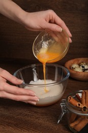 Photo of Woman mixing ingredients at wooden table, closeup. Cooking delicious eggnog