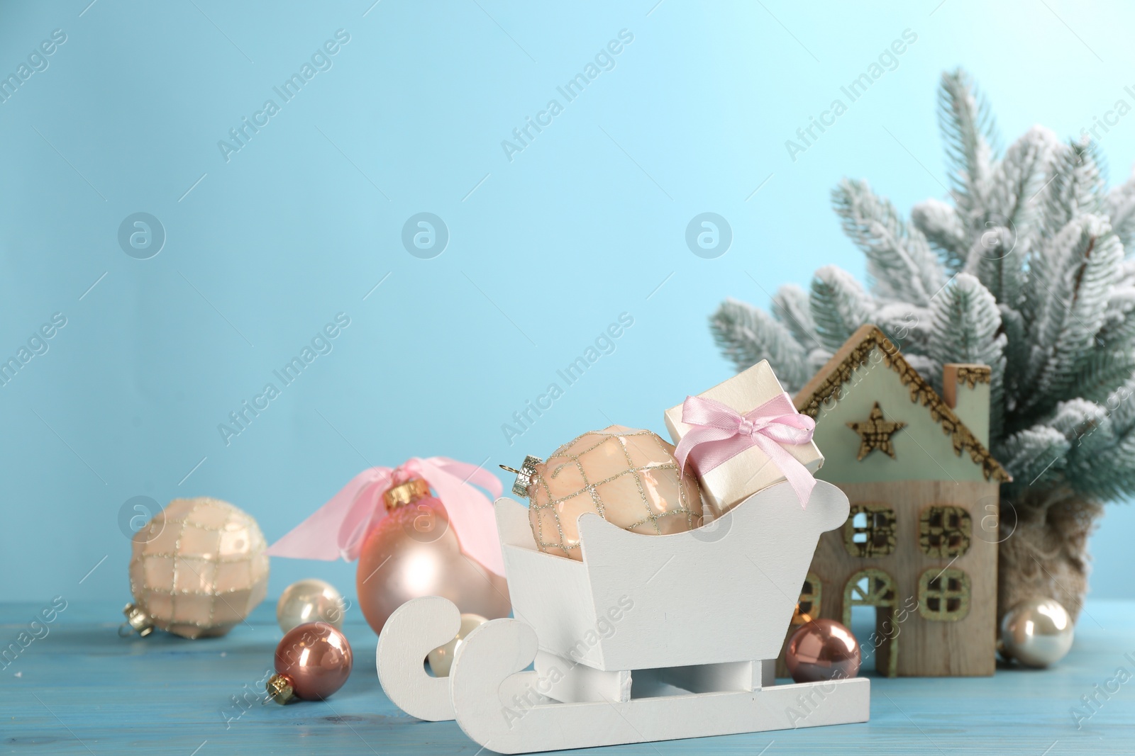 Photo of Beautiful Christmas composition with miniature sleigh on light blue table. Space for text