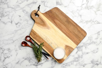 Photo of Cutting board, salt and thyme on white marble table, flat lay. Cooking utensil