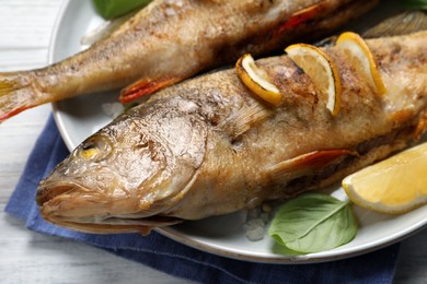 Photo of Tasty homemade roasted perches on white table, closeup. River fish
