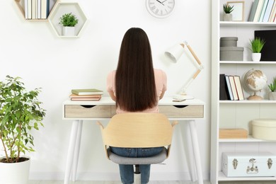 Photo of Home workplace. Woman working at comfortable desk in room, back view