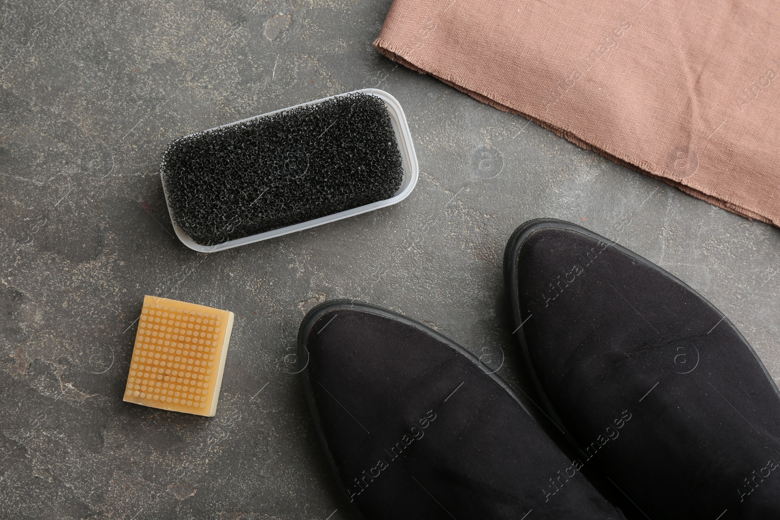 Photo of Stylish footwear with shoe care accessories on grey stone table, flat lay