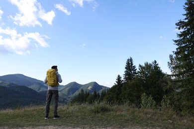 Photo of Tourist with backpack enjoying mountain landscape, back view. Space for text