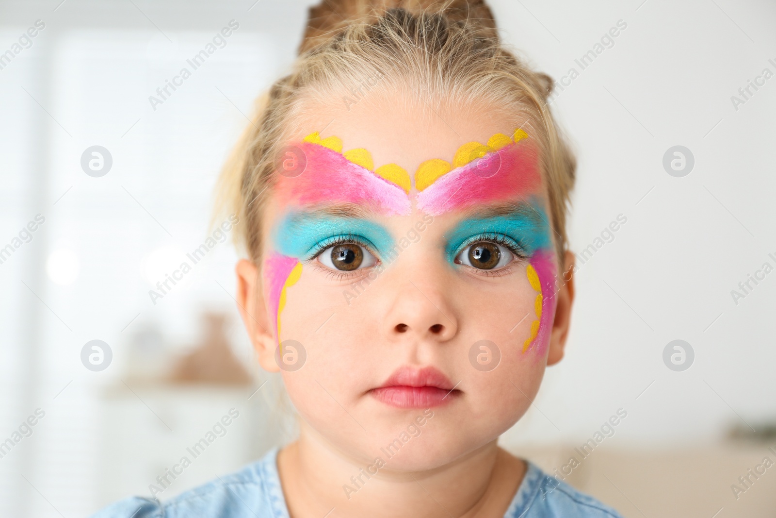 Photo of Cute little girl with face painting indoors