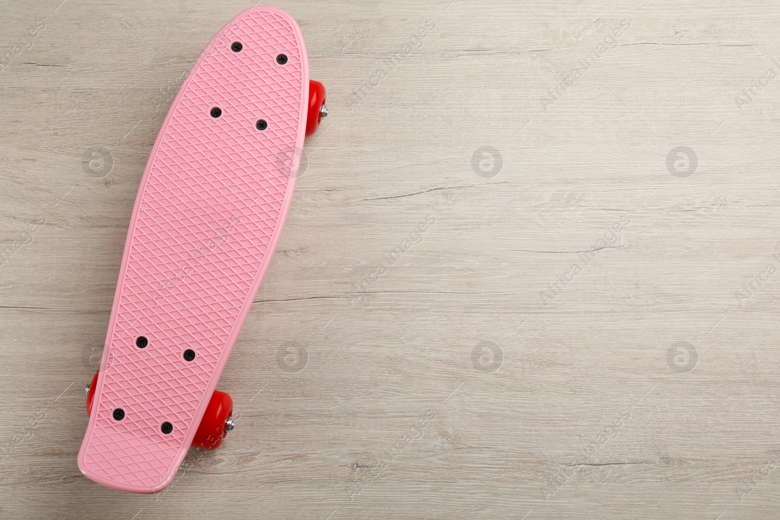 Photo of Pink skateboard on wooden background, top view. Space for text