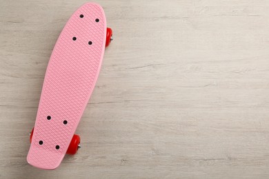 Photo of Pink skateboard on wooden background, top view. Space for text