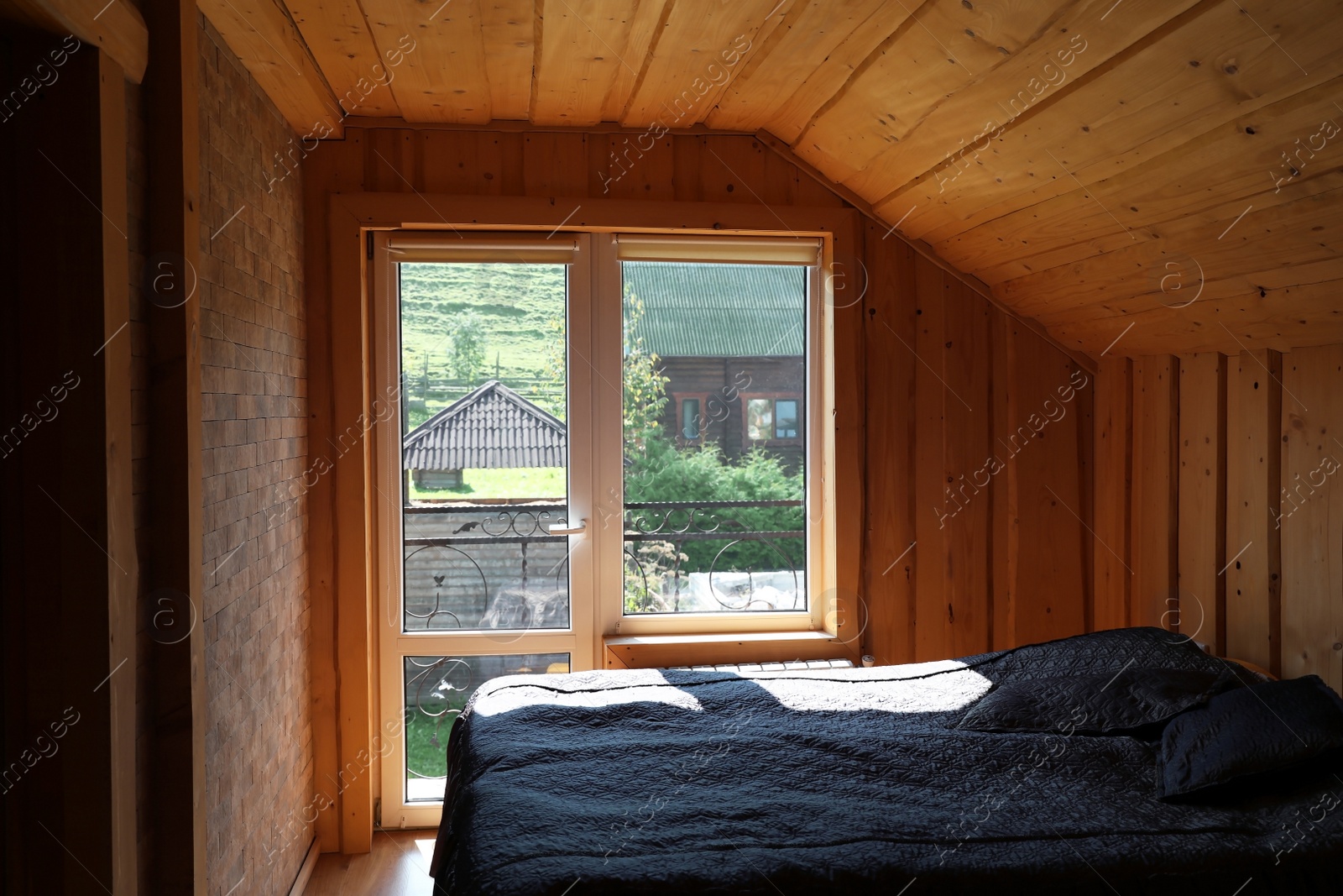 Photo of Cozy bedroom with window and wooden walls on sunny day