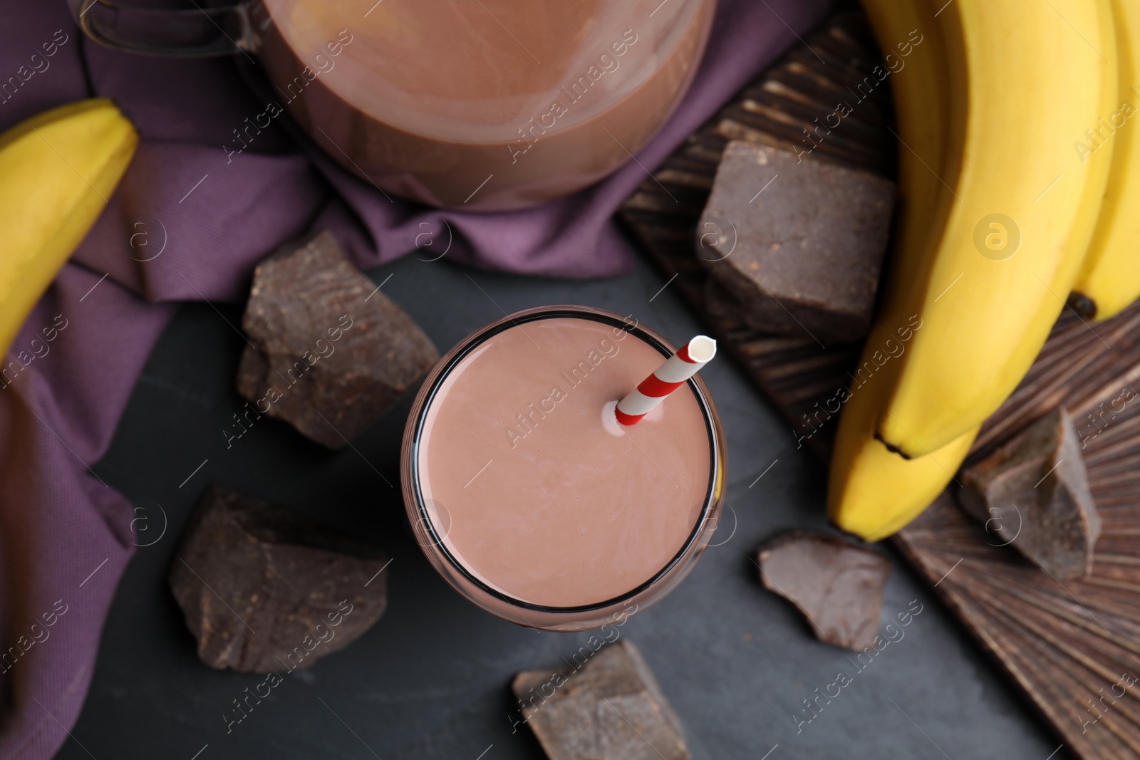 Photo of Fresh yummy chocolate milk on black table, flat lay