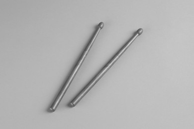 Two gray drum sticks on light background, top view