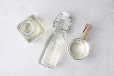 Vinegar in glass bottles and saucepan on light table, flat lay