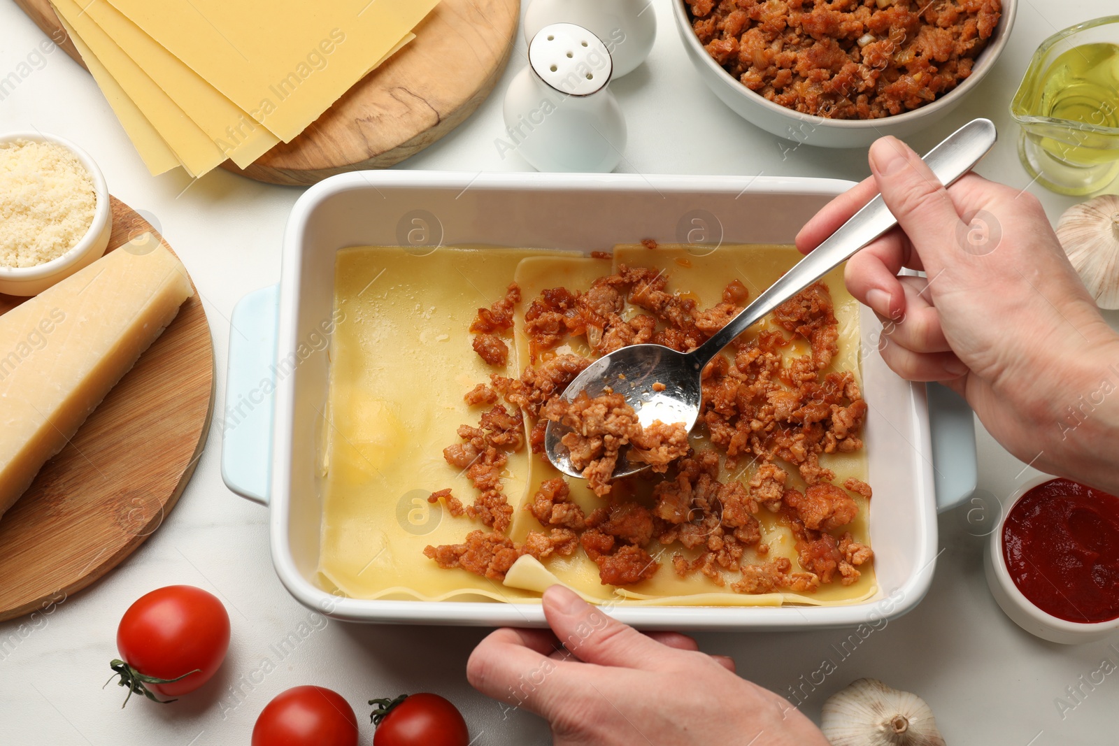 Photo of Woman making lasagna at white table, top view