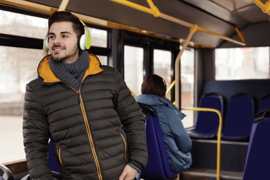 Photo of Young man listening to music with headphones in public transport