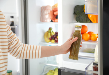 Photo of Young woman taking sauce out of refrigerator, closeup
