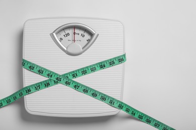 Weight loss concept. Scales and measuring tape on white background, top view. Space for text