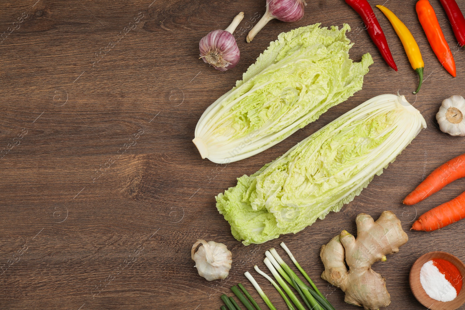 Photo of Flat lay composition with fresh Chinese cabbages and ingredients on wooden table. Space for text