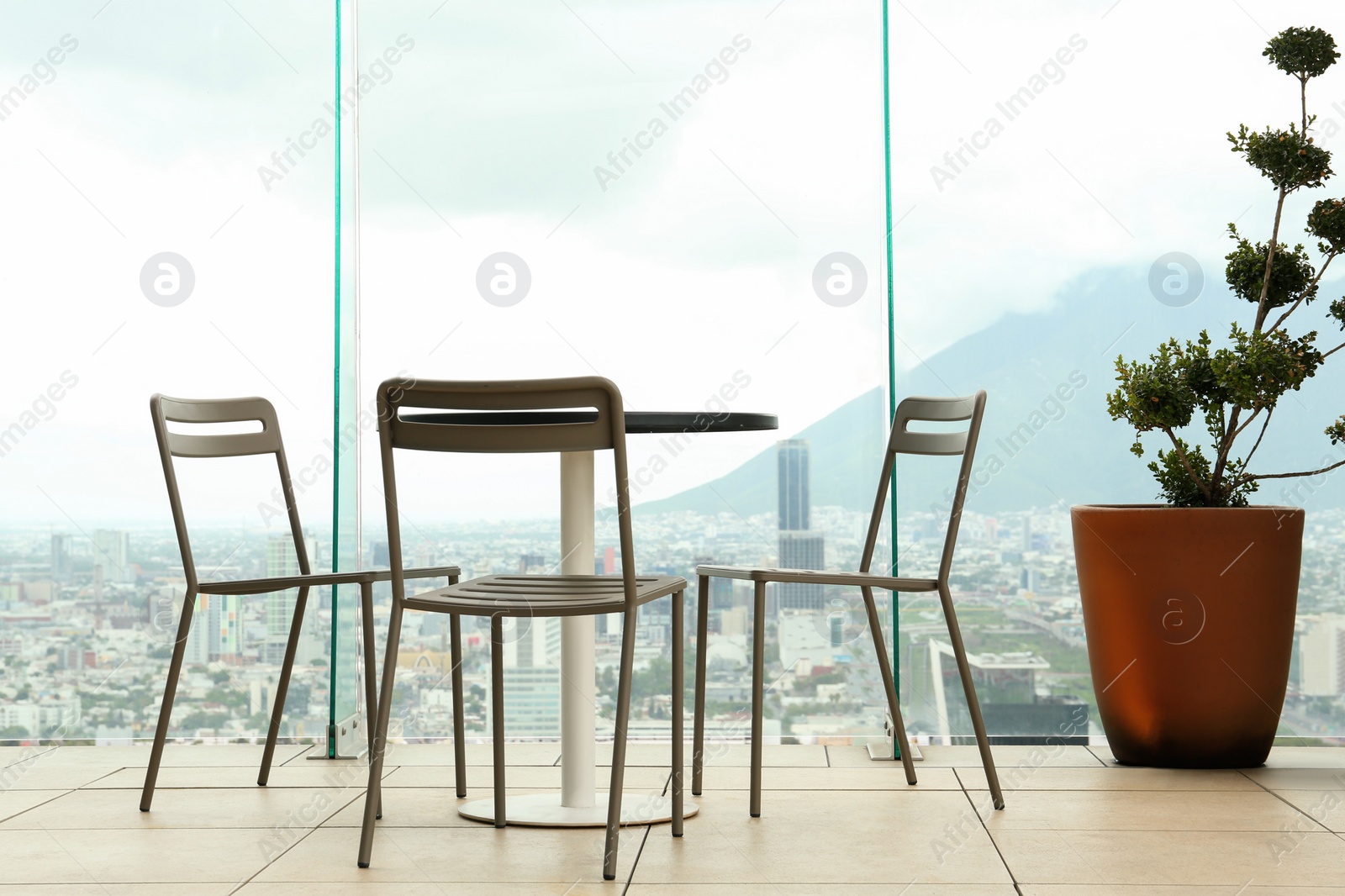 Photo of Coffee table and chairs against picturesque landscape of city in cafe