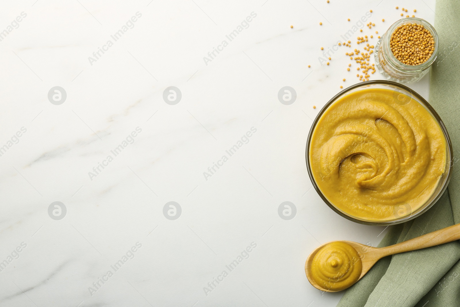 Photo of Tasty mustard sauce and dry seeds on white marble table, flat lay. Space for text