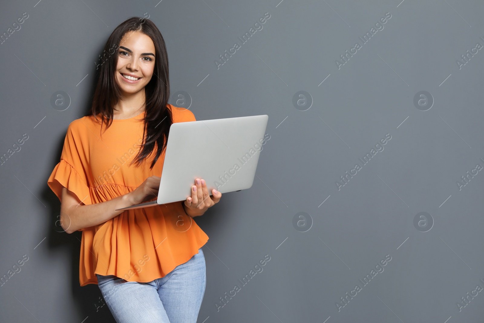 Photo of Young woman with modern laptop on grey background