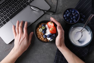 Photo of Woman with tasty granola at workplace, top view