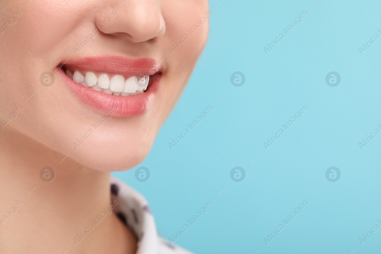 Photo of Woman with clean teeth smiling on light blue background, closeup. Space for text